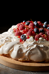 Image showing pavlova meringue cake with berries on wooden board