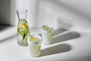 Image showing glasses with lemon water and cucumber on table