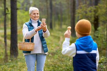 Image showing grandmother photographing grandson with mushrooms