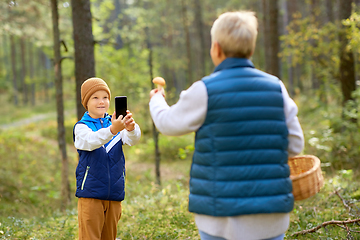 Image showing grandson photographing grandmother with mushroom