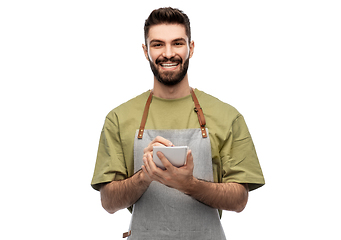 Image showing smiling waiter in apron taking notes to notepad