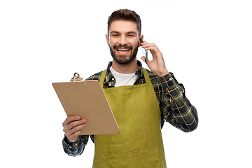 Image showing male gardener with clipboard calling on smartphone