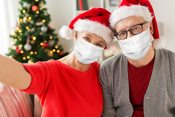 Image showing senior couple in masks taking christmas selfie