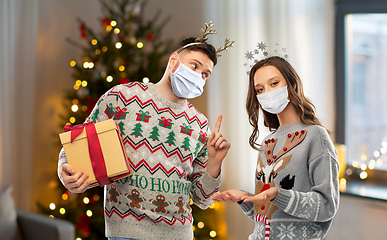 Image showing couple in masks, christmas sweaters with gifts