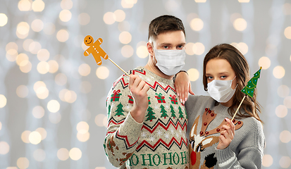 Image showing couple in medical masks and christmas sweaters