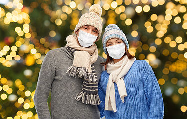 Image showing couple in masks and winter clothes on christmas