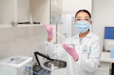 Image showing asian female scientist in mask working on vaccine