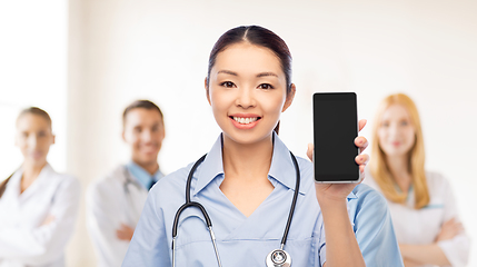 Image showing happy asian female doctor or nurse with smartphone