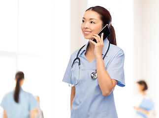 Image showing asian nurse calling on smartphone at hospital