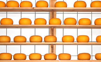 Image showing Yellow round Cheeses riping on the shelves