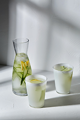 Image showing glasses with lemon water and cucumber on table