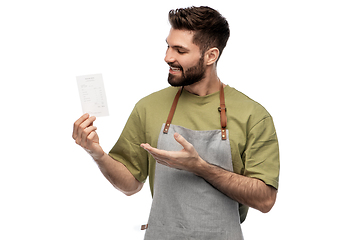 Image showing happy smiling barman in apron with bill