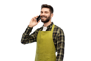 Image showing happy male gardener in apron calling on smartphone