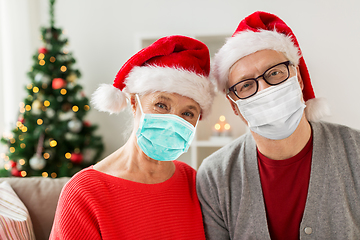 Image showing senior couple in masks and santa hats on christmas