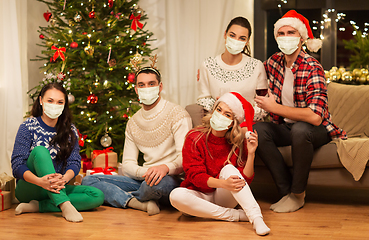 Image showing friends in masks drinking wine on christmas