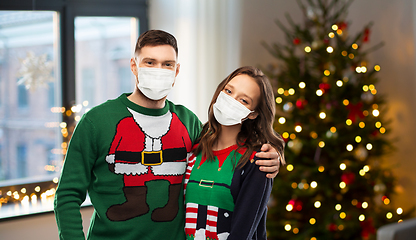 Image showing couple in masks and sweaters on christmas