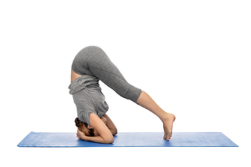 Image showing woman making yoga in headstand pose on mat