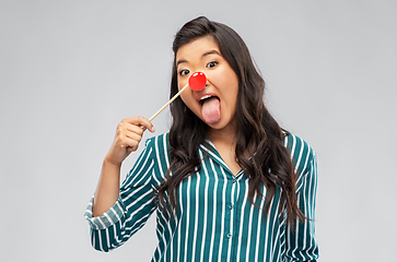 Image showing asian woman with red clown nose showing tongue