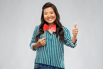 Image showing happy asian woman with party bow showing thumbs up