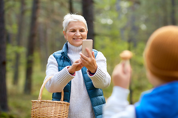 Image showing grandmother photographing grandson with mushrooms