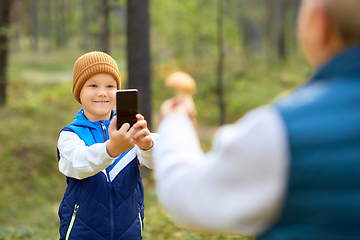 Image showing grandson photographing grandmother with mushroom