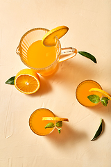 Image showing glasses with orange juice and peppermint on table