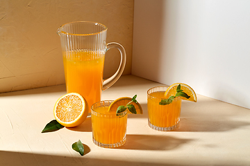 Image showing glasses with orange juice and peppermint on table