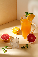 Image showing orange juice, grapefruit and ice in glass on table