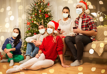 Image showing friends in masks drinking wine on christmas