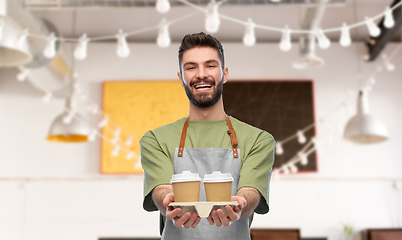 Image showing happy smiling barman in apron with takeaway coffee