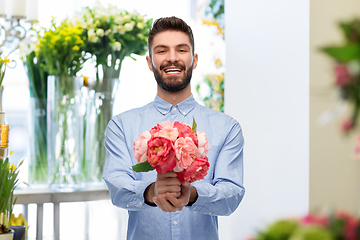 Image showing happy smiling man with peonies at flower shop