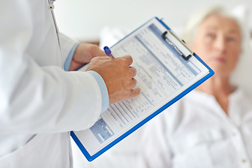 Image showing senior woman and doctor with clipboard at hospital