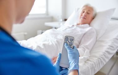 Image showing nurse adjusting bed for senior woman at hospital