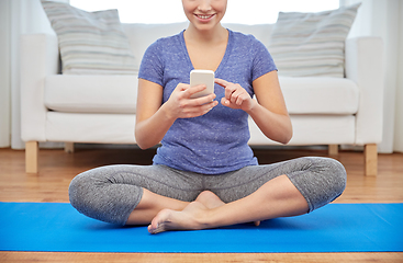 Image showing woman with smartphone sitting on mat at home