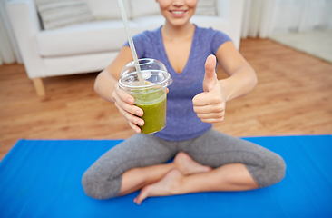 Image showing happy woman with cup of smoothie showing thumbs up