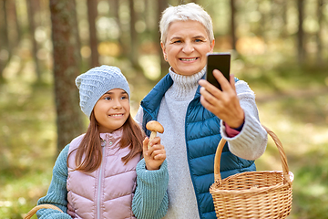 Image showing grandma with granddaughter taking selfie in forest