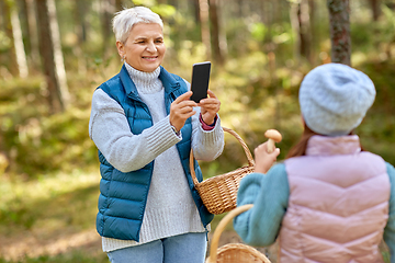 Image showing grandma photographing granddaughter with mushrooms