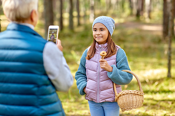 Image showing grandma photographing granddaughter with mushrooms