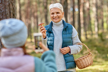 Image showing granddaughter photographing grandma with mushrooms