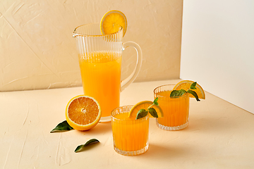 Image showing glasses with orange juice and peppermint on table