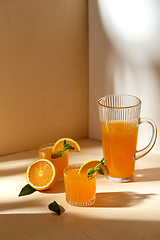 Image showing glasses with orange juice and peppermint on table