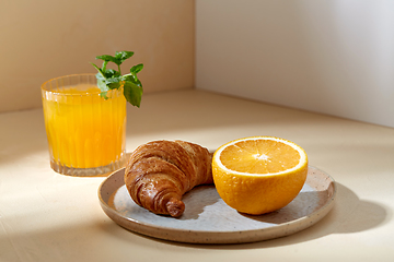 Image showing glass of orange juice and croissant on plate