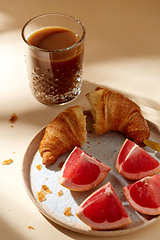 Image showing glass of coffee, croissant and grapefruit on table