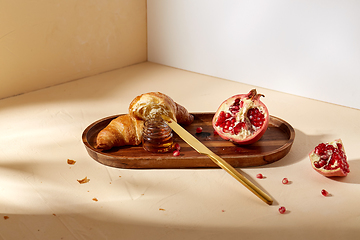 Image showing croissant, pomegranate and honey on wooden tray