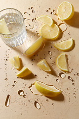 Image showing glass of water and lemon slices on wet table