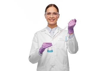 Image showing female scientist in goggles with chemical in flask