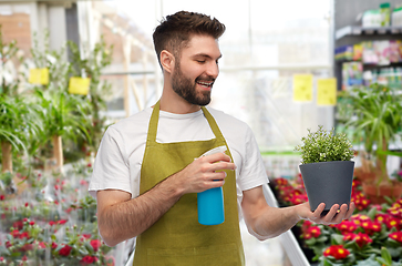 Image showing happy male gardener moisturizing flower at shop