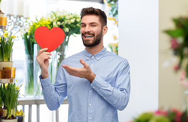 Image showing smiling young man with red heart at flower shop