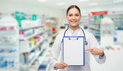 Image showing happy female doctor with clipboard at pharmacy