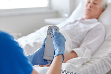 Image showing nurse adjusting bed for senior woman at hospital